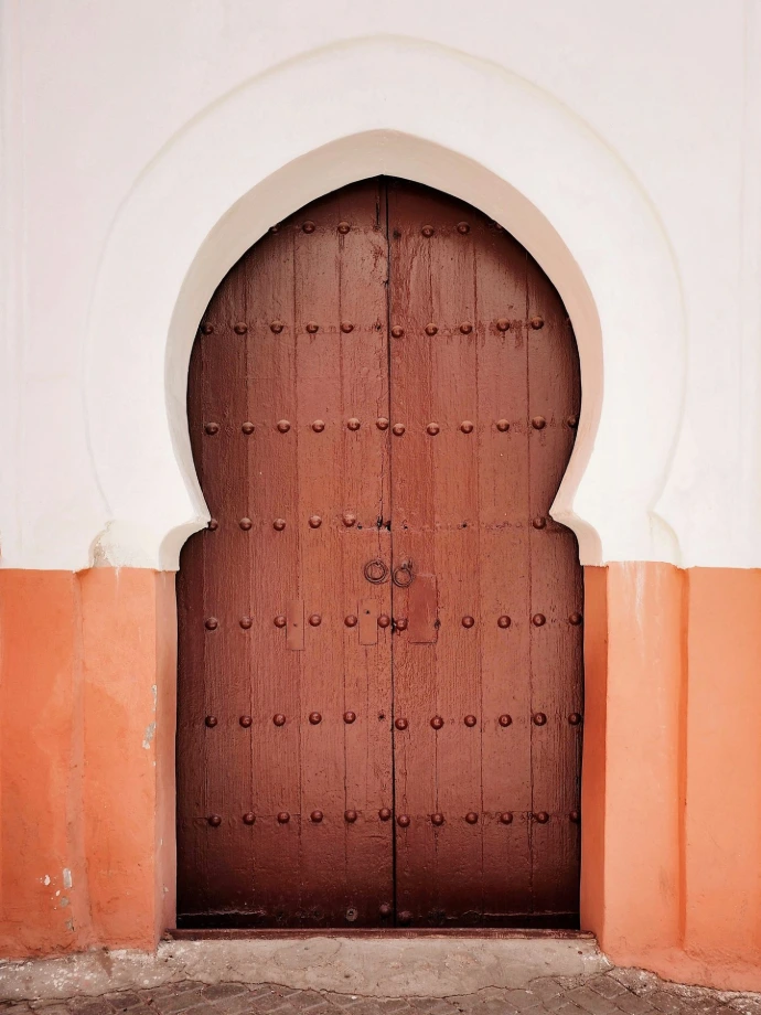 A large wooden door in front of a white building